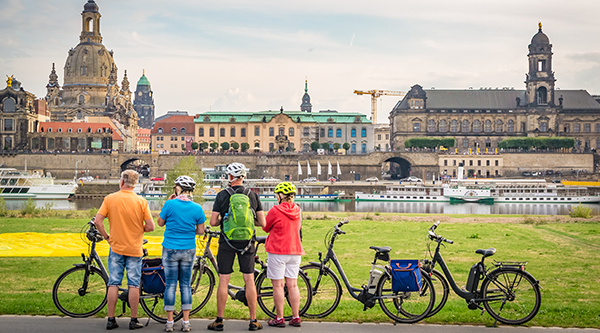 Group of cyclists on the banks of the river Elbe, in the background the silhouette of Dresden - © The Photographer – stock.adobe.com