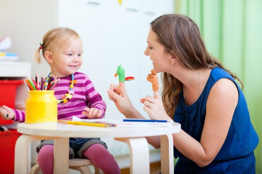 Junge Frau spielt mit kleinem Mädchen am Tisch