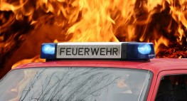 Bild eines Feuerwehrautos, im Hintergrund Flammen.