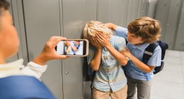 Foto: ein Schüler fillmt wie ein Schüler einen anderen Schüler bedrängt