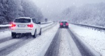 Bild einer verschneiten Straße, auf der zwei Autos fahren.