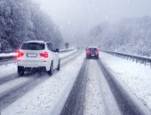 Bild einer verschneiten Straße, auf der zwei Autos fahren.