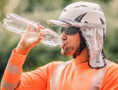 Bild eines Mannes, der Sonnenschutz und eine Sonnenbrille trägt und aus einer Wasserflasche trinkt.