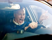 Bild eines Autofahrers, der wütend in seinem Auto sitzt. Mit einer Hand hält er das Lenkrad, mit der anderen Hand gestikuliert er.