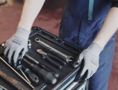 Foto: Ein Arbeiter mit Handschuhen nimmt Werkzeug in die Hand