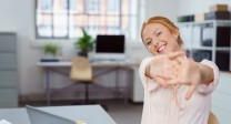 Eine Frau im Büro streckt glücklich die Hände aus.