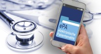 Das Bild zeigt eine Hand, die ein Smartphone hält. Auf dem Bildschirm des Smartphones ist eine Anwendung mit der Aufschrift „ePA – elektronische Patientenakte“ zu sehen. Im Hintergrund liegen medizinische Utensilien, wie ein Stethoskop und Tablettenblister. 